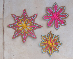 ID: Handmade multicolor snowflakes with cardboard and yarn.