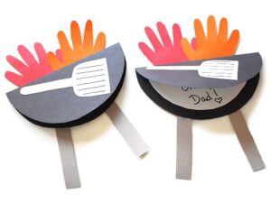 two handmade Fathers Day cards with two handprints in red and orange coming out of a grill.